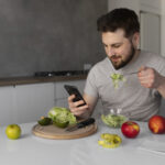 young-man-eating-checking-his-smartphone