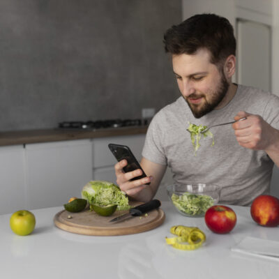 young-man-eating-checking-his-smartphone